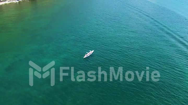 Aerial footage of a white boat on the water of sea. Pure water. Rowing. View from above. Drone footage.