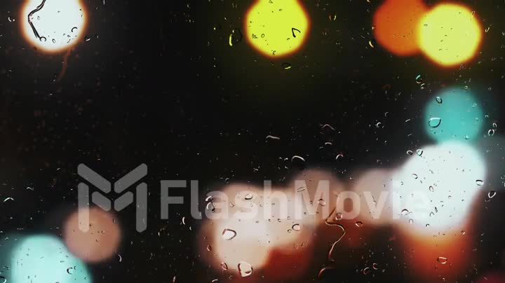 Raindrops on a car window with blurred background of street traffic lights