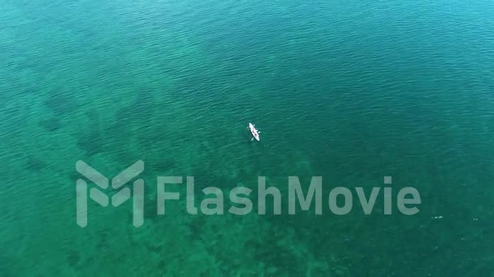 Aerial footage of a white boat on the water of lake. Pure water. Rowing. View from above. Drone footage.