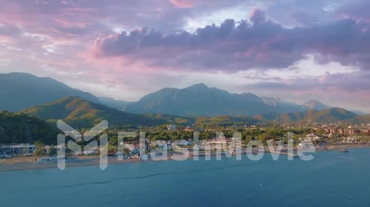 Aerial drone video footage flight over blue sea. Coast and mountains in the background. Seascape. Sunset. Hotels. Pool
