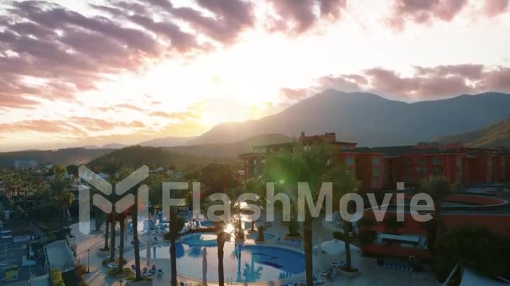 Beautiful purple pink clouds at sunset. Mountain landscape. The territory of the hotel. Green area. Drone video footage
