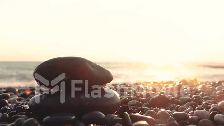 Beautiful view of the sunset at the sea from the shore, pebble stone in the foreground
