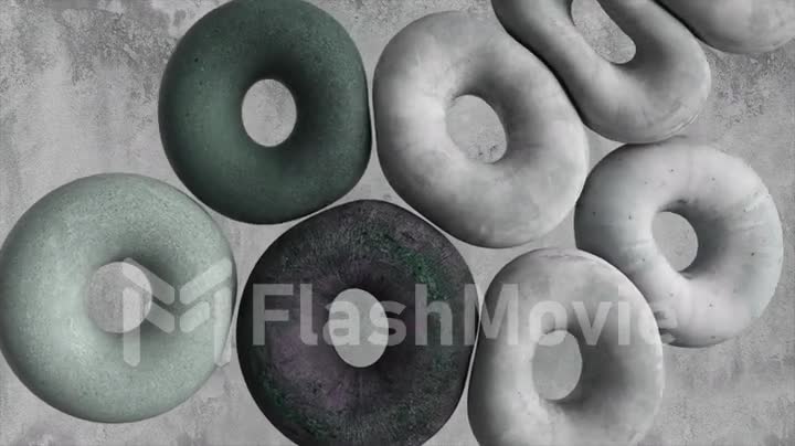 Soft gray donuts fly against the background of a concrete wall. Donuts collide with each other, push off and join