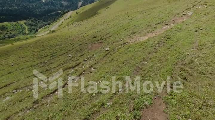 Flight over the top of the hill. The ground is covered with green grass. Mountain landscape. FPV Drone video 4k footage