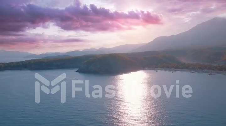 Aerial drone video footage. Seascapes at sunset. Blue sea and green trees on the shore. Mountains in the background
