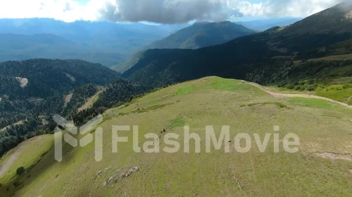 Aerial POV footage of flight over the hills. Mountain landscape around. Blue sky white clouds. FPV Drone video footage