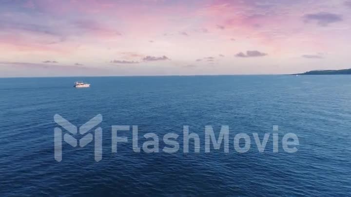 The yacht sails on the sea at sunset. Aerial drone video footage. Blue sea and pink sky. Beautiful clouds. Seascape.