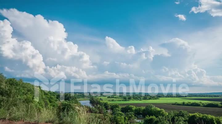 Beautiful landscape time lapse, cumulus clouds over the river and field, precipitation formation