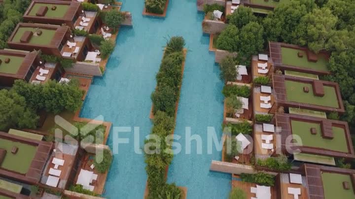 Aerial video filming from a drone of the hotel territory. Green trees and shrubs. Pool, beach umbrellas, sun loungers.