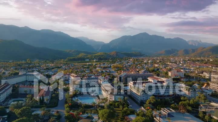 Sunset flight over hotels and mountains. Beautiful purple pink clouds. Roofs of hotels. Aerial drone footage
