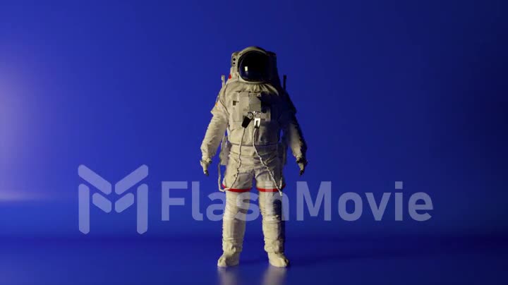 Abstract space concept. The astronaut stands on a blue isolated background with changing lighting. Chroma key. Helmet.