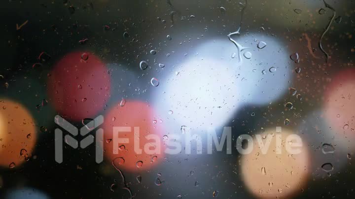 Raindrops on a car window with blurred background of street traffic lights